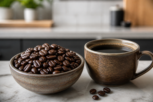 Dark roast coffee beans beside a cup of brewed black coffee